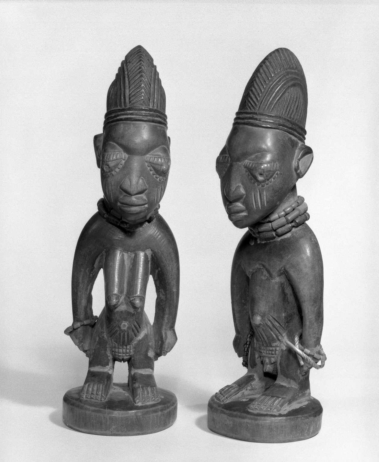 A pair of traditional carved wooden Yoruba ibeji statues.