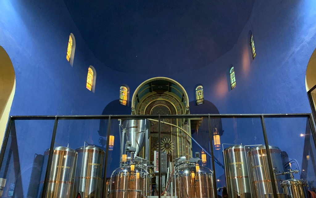 large altar with blue walls and stained glass windows with beer barrels on top