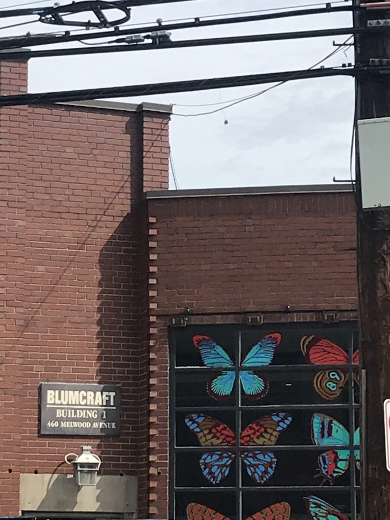 close up of front of brick building with large colorful butterfly art in front window panes